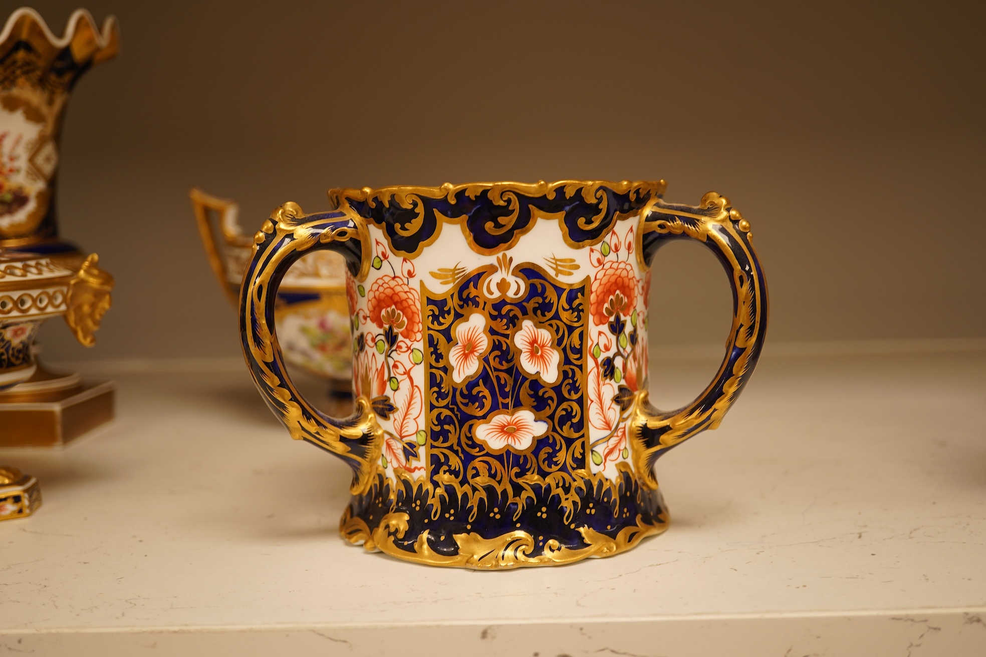A collection of Royal Crown Derby, to include a two handled bowl, a fluted pedestal vase, saucer with landscape central cartouche etc (5). Vase 19cm high.